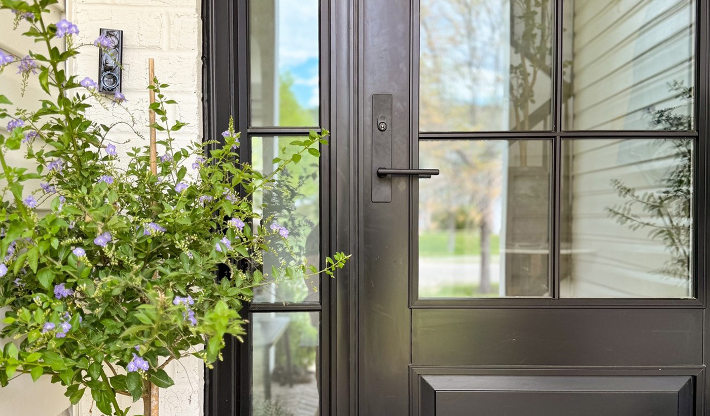 A modern wood front door on a white brick home