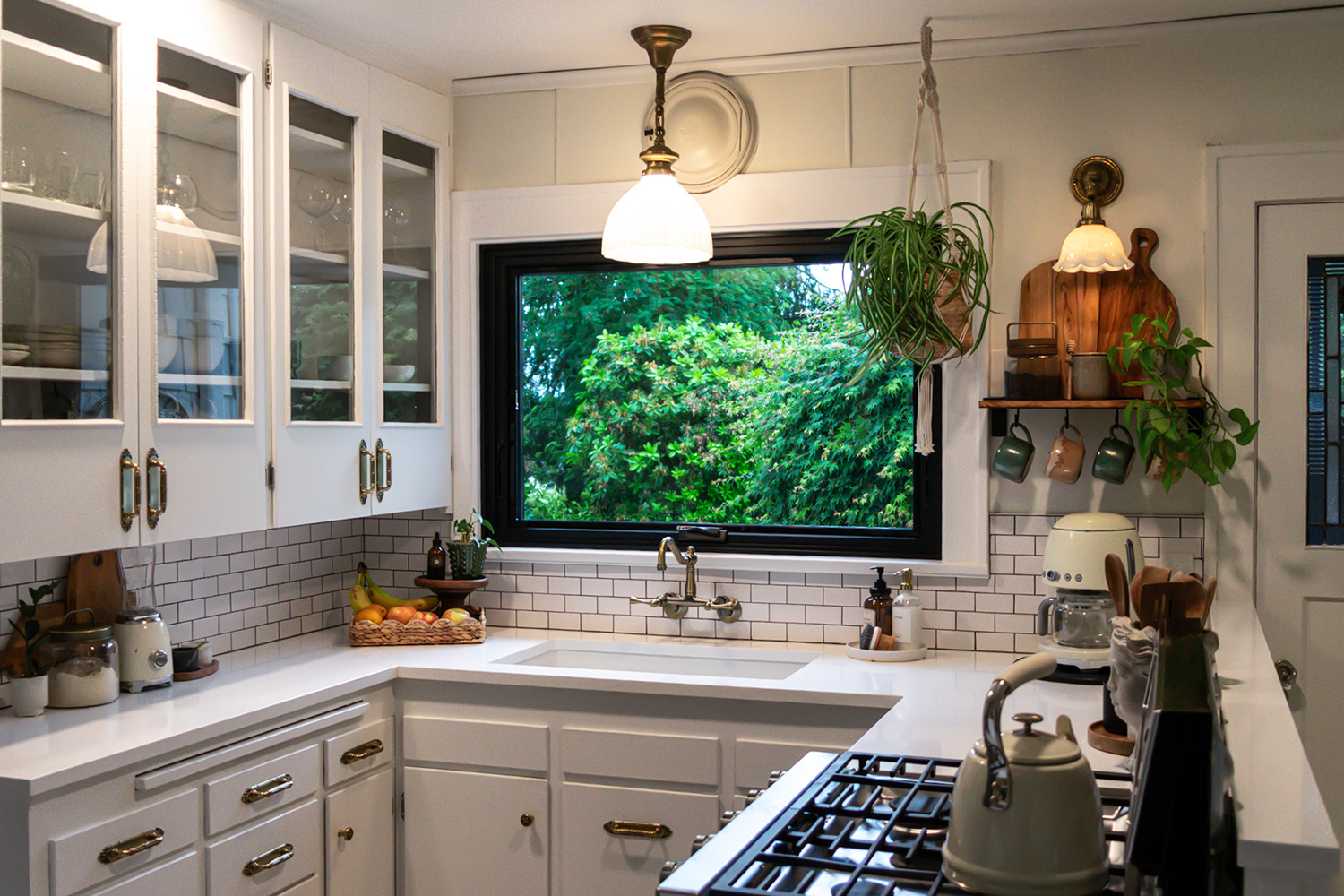 A picture window on top of the sink bringing the outside warmth into the kitchen with all white marbles