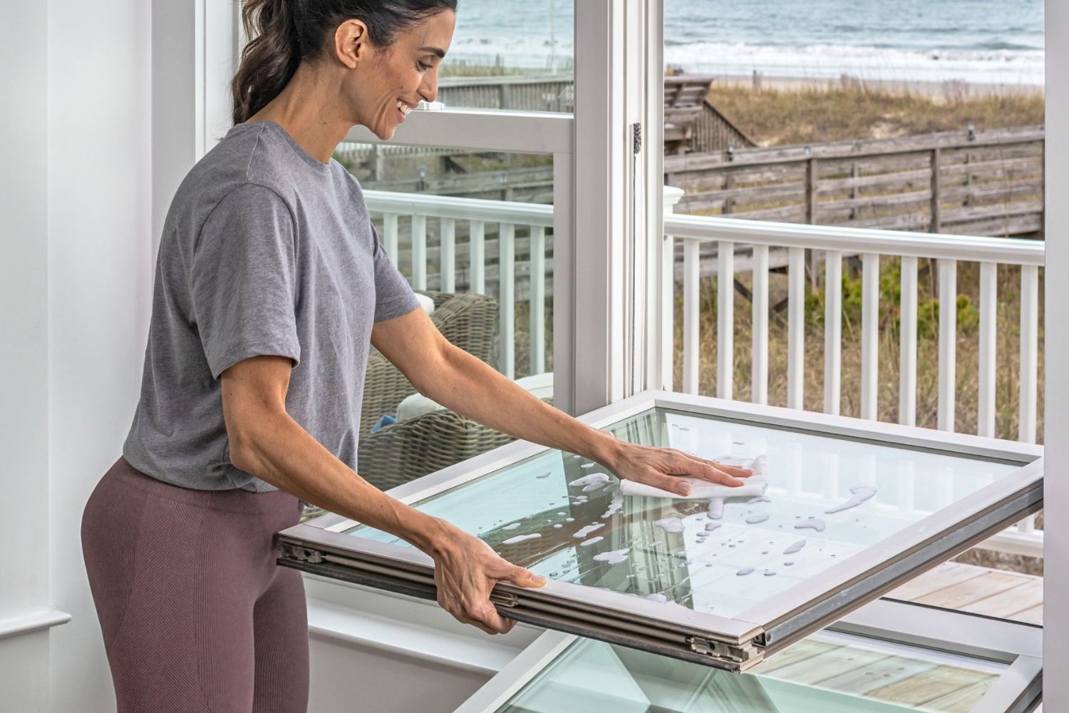Woman cleaning her windows from inside her home.