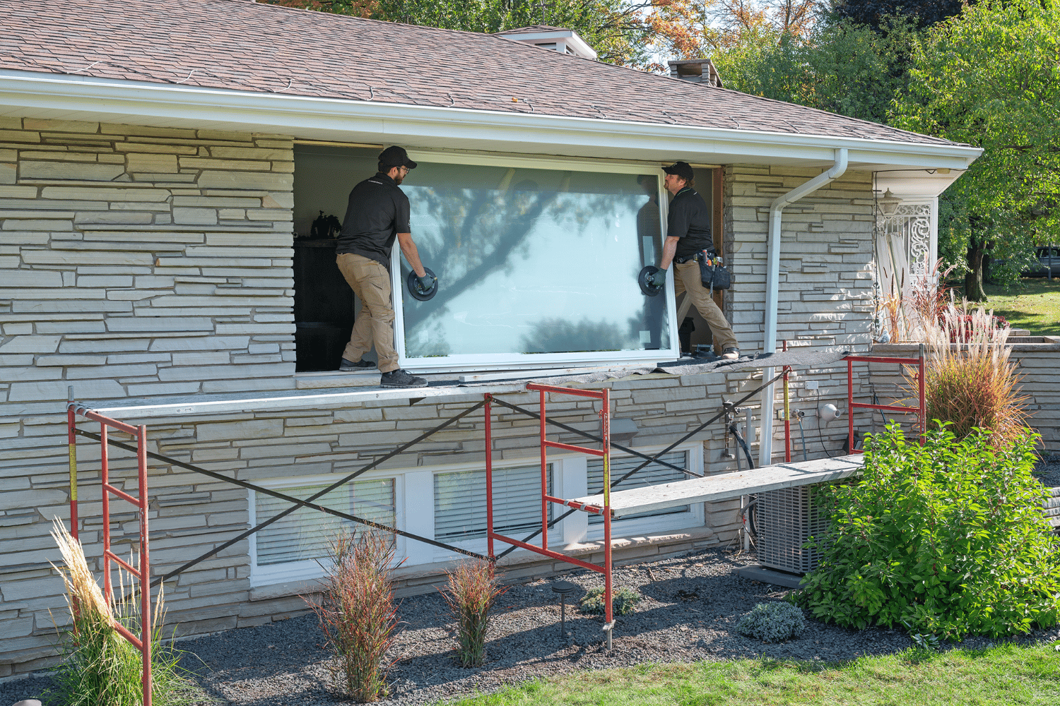 Renewal by Andersen's Installers lifting a window to be installed