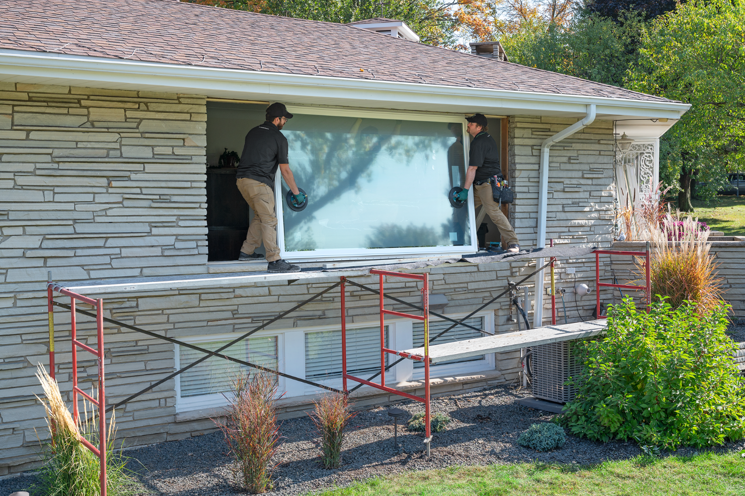 Renewal by Andersen's Installers lifting a window to be installed