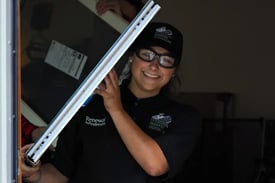 A female installer carries a window out of the Kansas City Hope Lodge