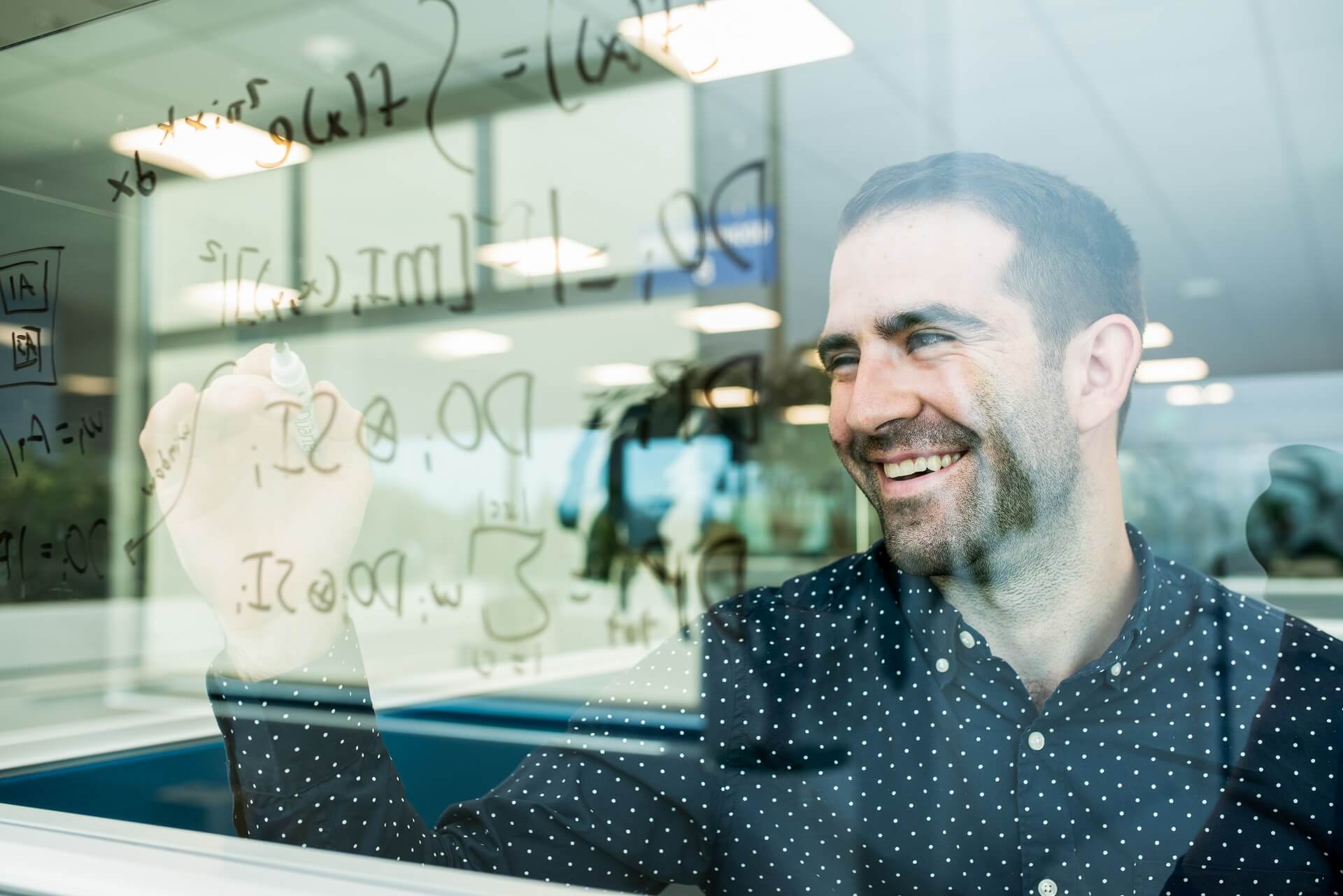 An AMSL software engineer works on a see-through whiteboard