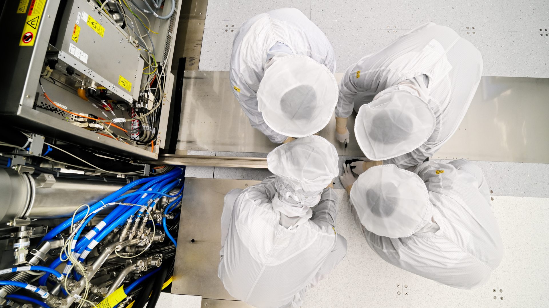 bird’s eye view of four cleanroom engineers working on the wafer stage of an ASML EUV system. 