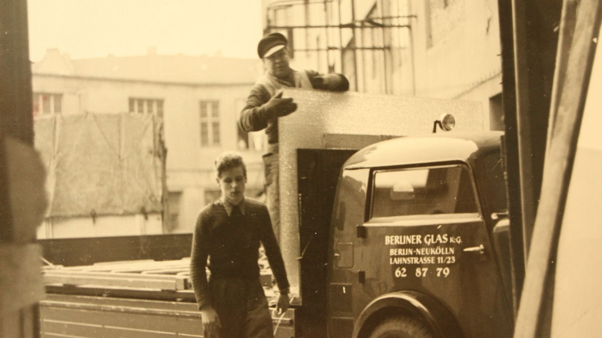 Old-fashioned picture of two men loading glass onto a Berliner Glas truck.