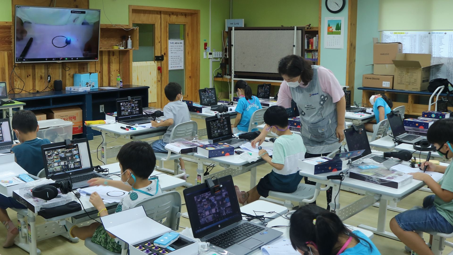 children sitting at desks in classroom with teacher