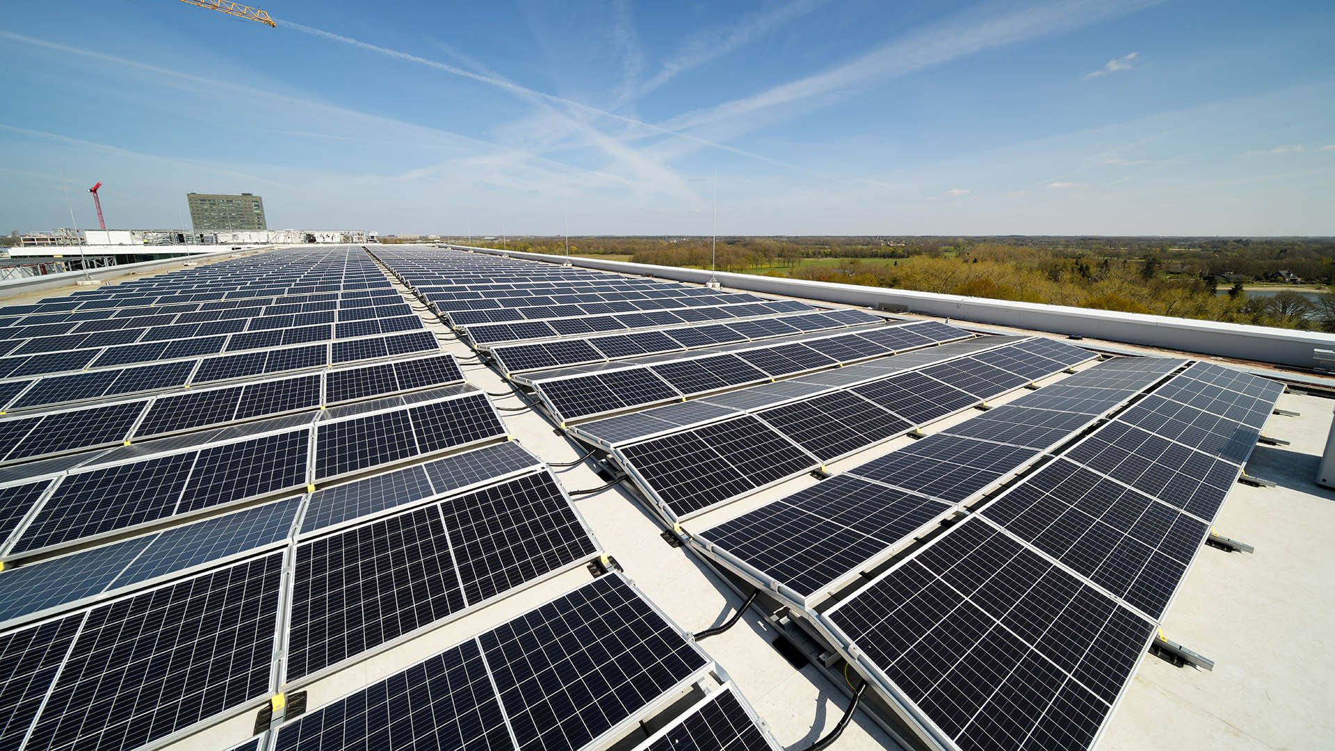 Rows of solar panels on a building roof under a blue sky