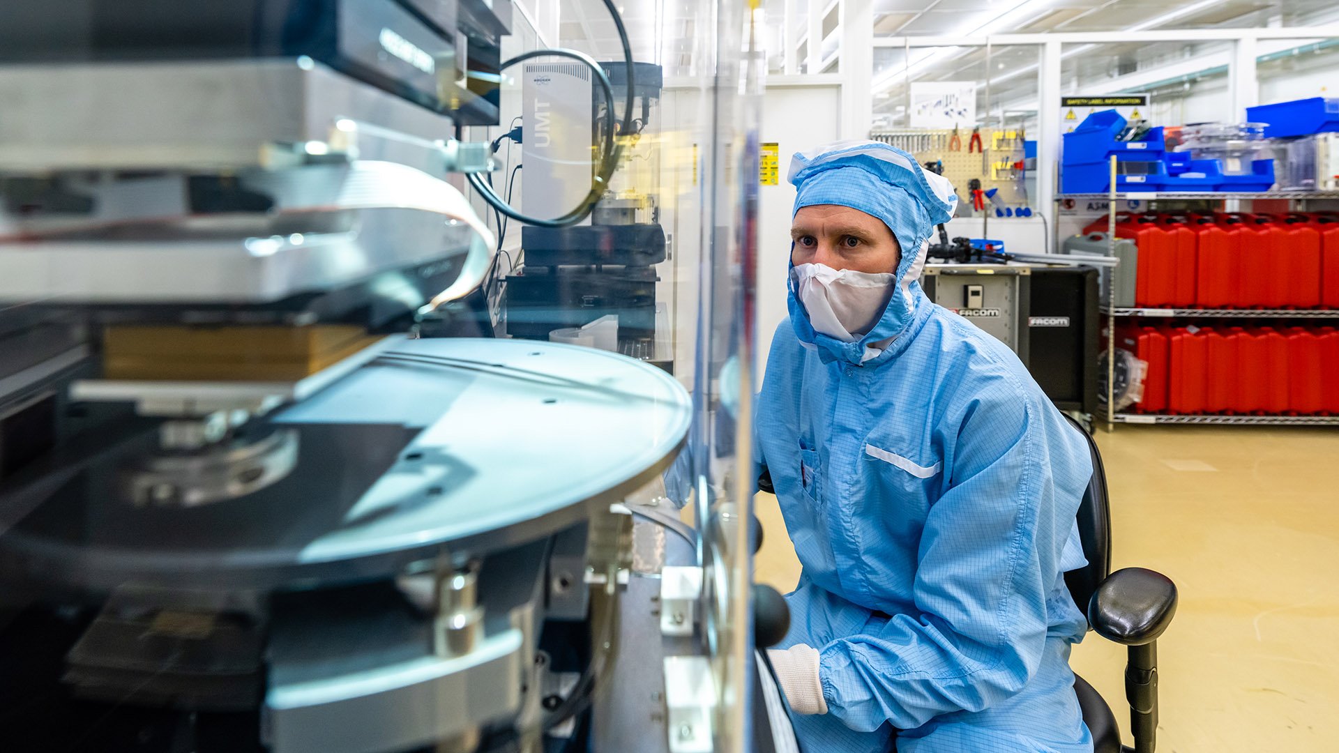 Person in protective clothing observing a lithography machine