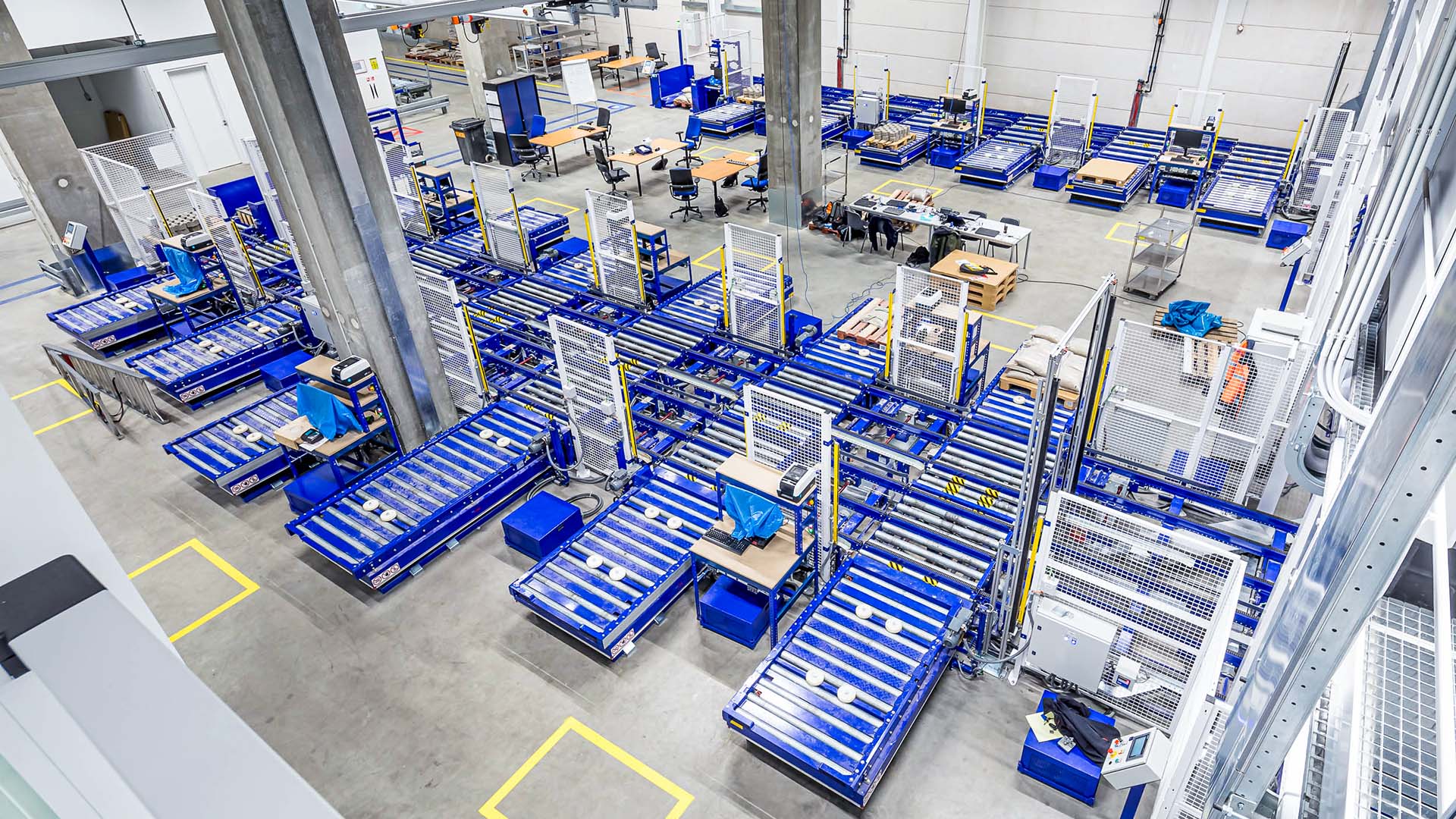 Overhead view of ASML's warehouse logistics, showcasing rows of blue storage racks with equipment and components.