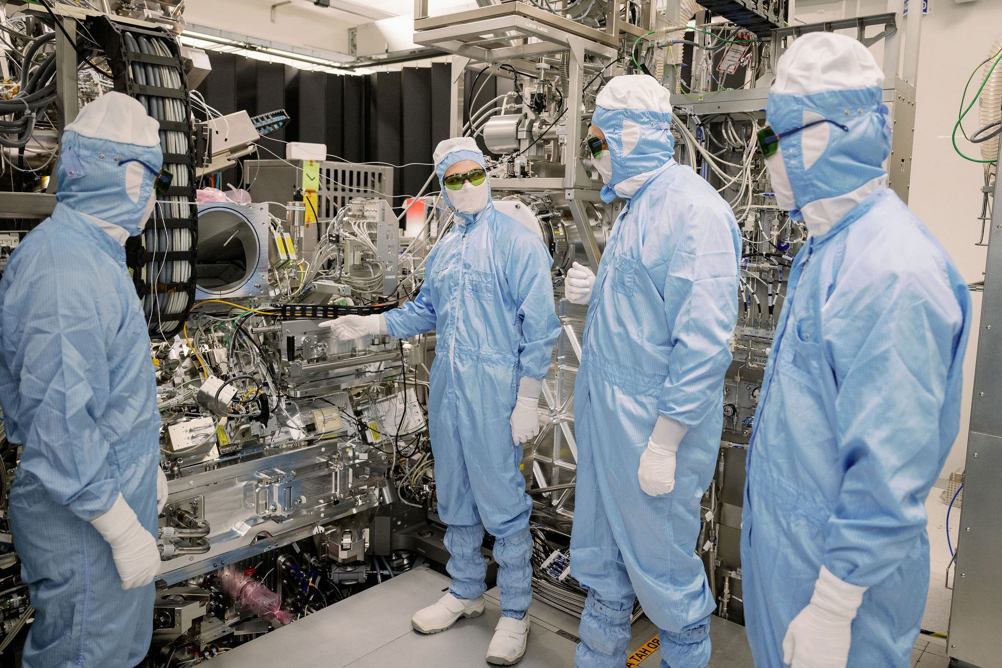 ASML technicians examining a machine part in a cleanroom ASML technicians examining a machine part in a cleanroom