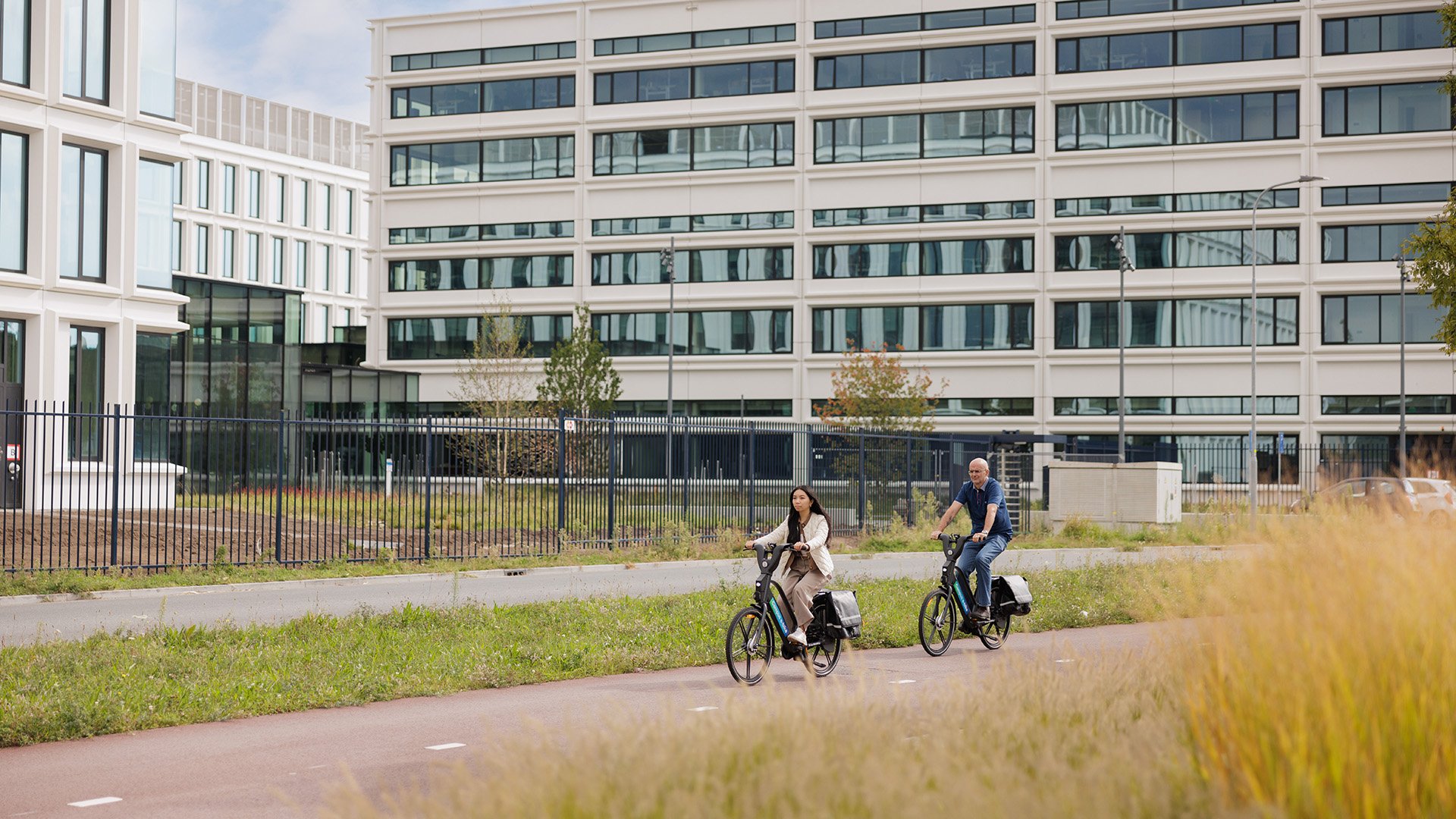 People cycling past an ASML building People cycling past an ASML building