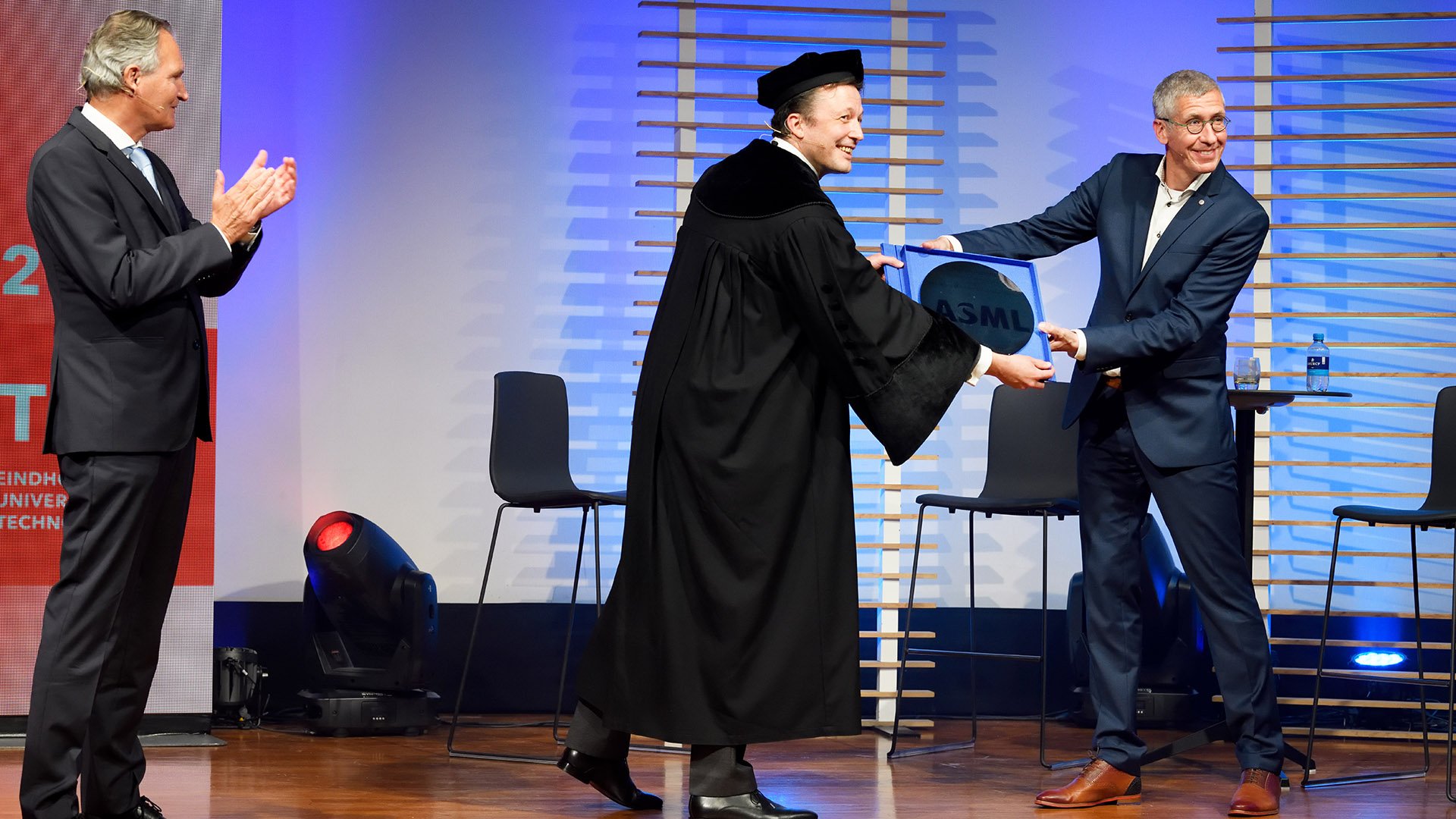 ASML vice president Frank Schuurmans symbolically hands over a present to TU/e president Robert-Jan Smits and TU/e professor Martijn Heck, scientific director of the Eindhoven Hendrik Casimir Institute. ASML vice president Frank Schuurmans symbolically hands over a present to TU/e president Robert-Jan Smits and TU/e professor Martijn Heck, scientific director of the Eindhoven Hendrik Casimir Institute.