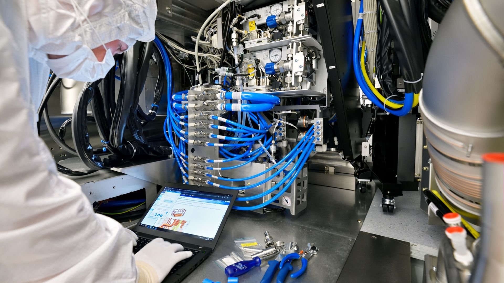 An ASML EUV customer support engineer troubleshoots a machine inside a cleanroom