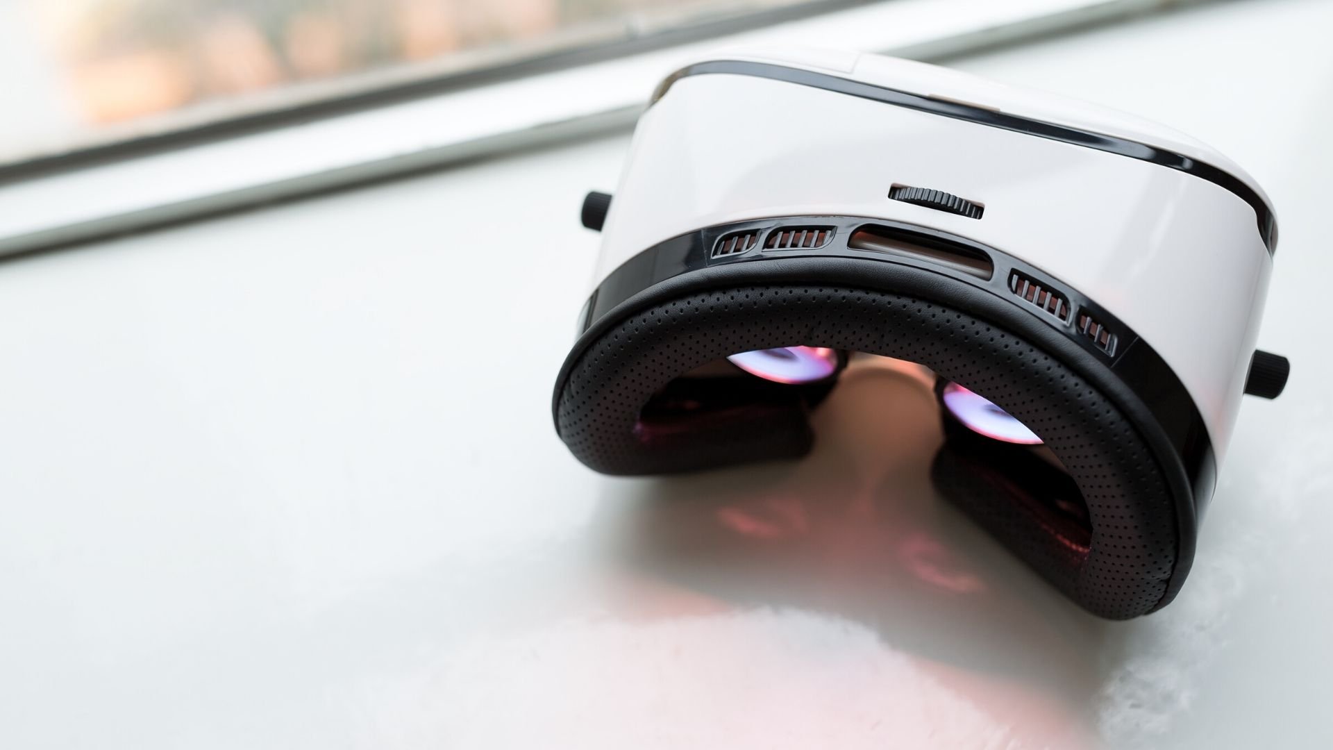 A white VR headset lies on a windowsill.
