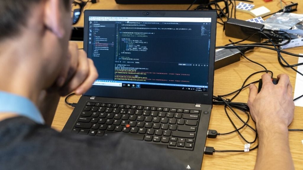 A software developer sits in front of a screen showing code at ASML's Digital Gold Hackathon in November 2018. 