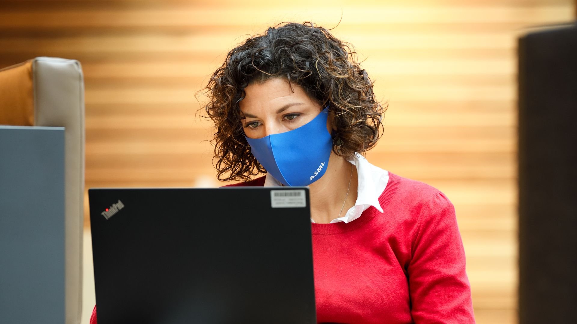 A woman in an ASML facemask works on her laptop