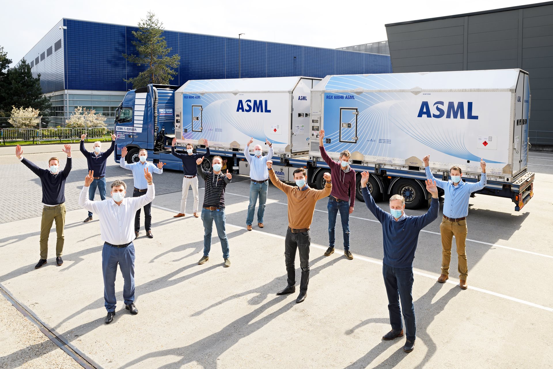 ASML engineers celebrate first shipment through pilot program, stand before system on the truck.