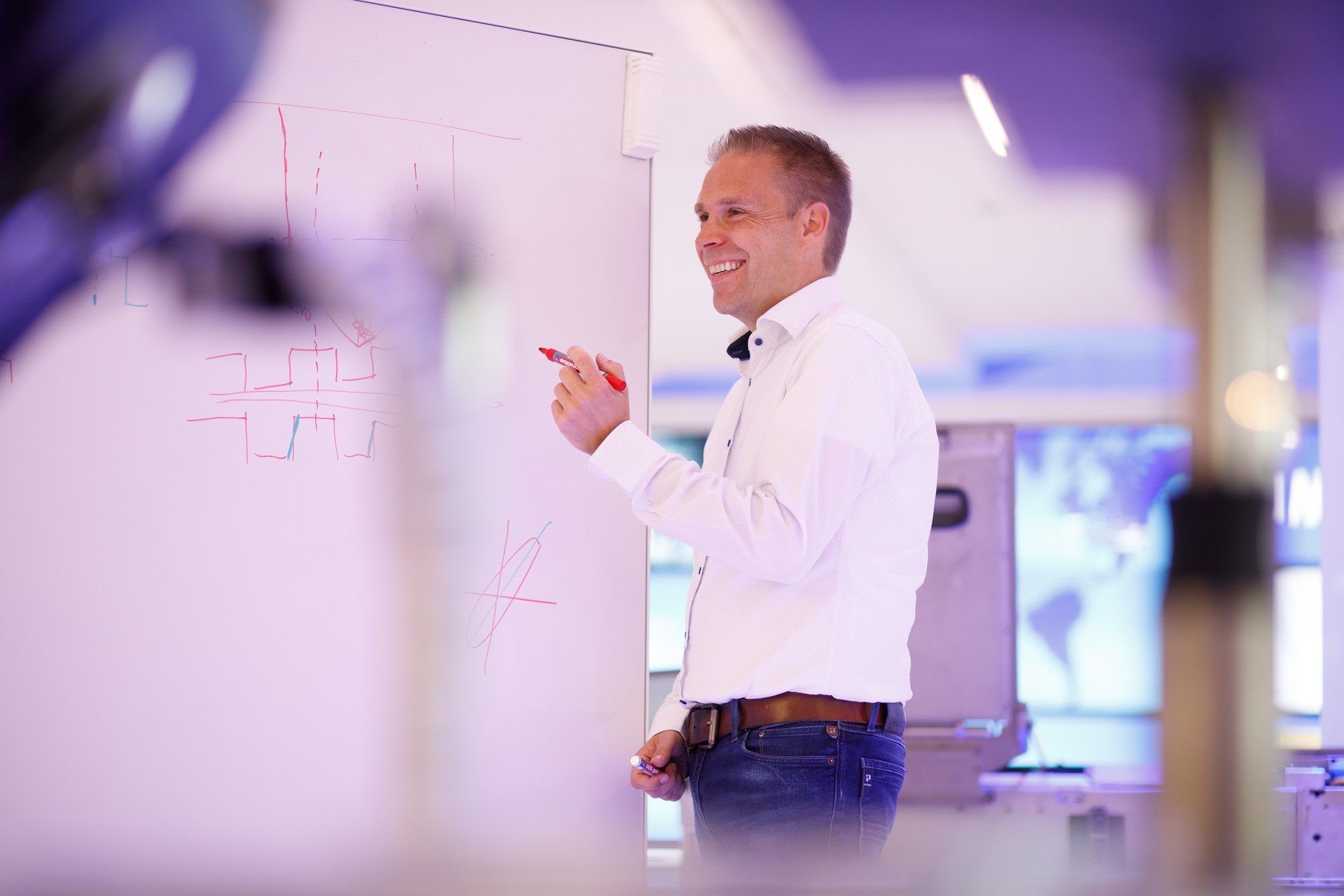 ASML Fellow Simon Mathijssen in a classroom points to a whiteboard which has drawings on it.
