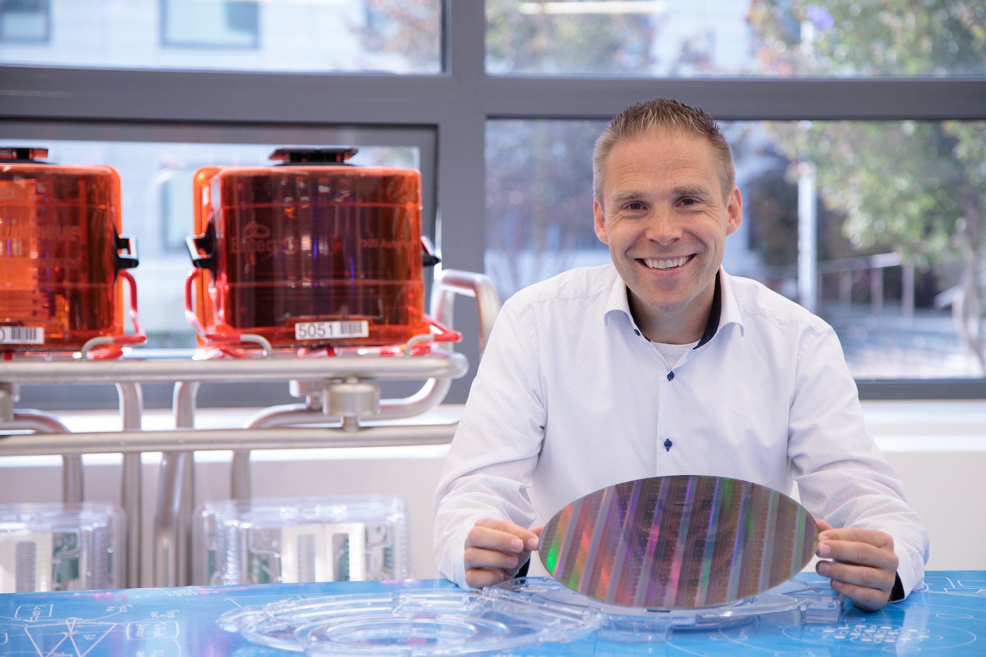 ASML Fellow Simon Mathijssen holds a multi-colored microchip wafer.