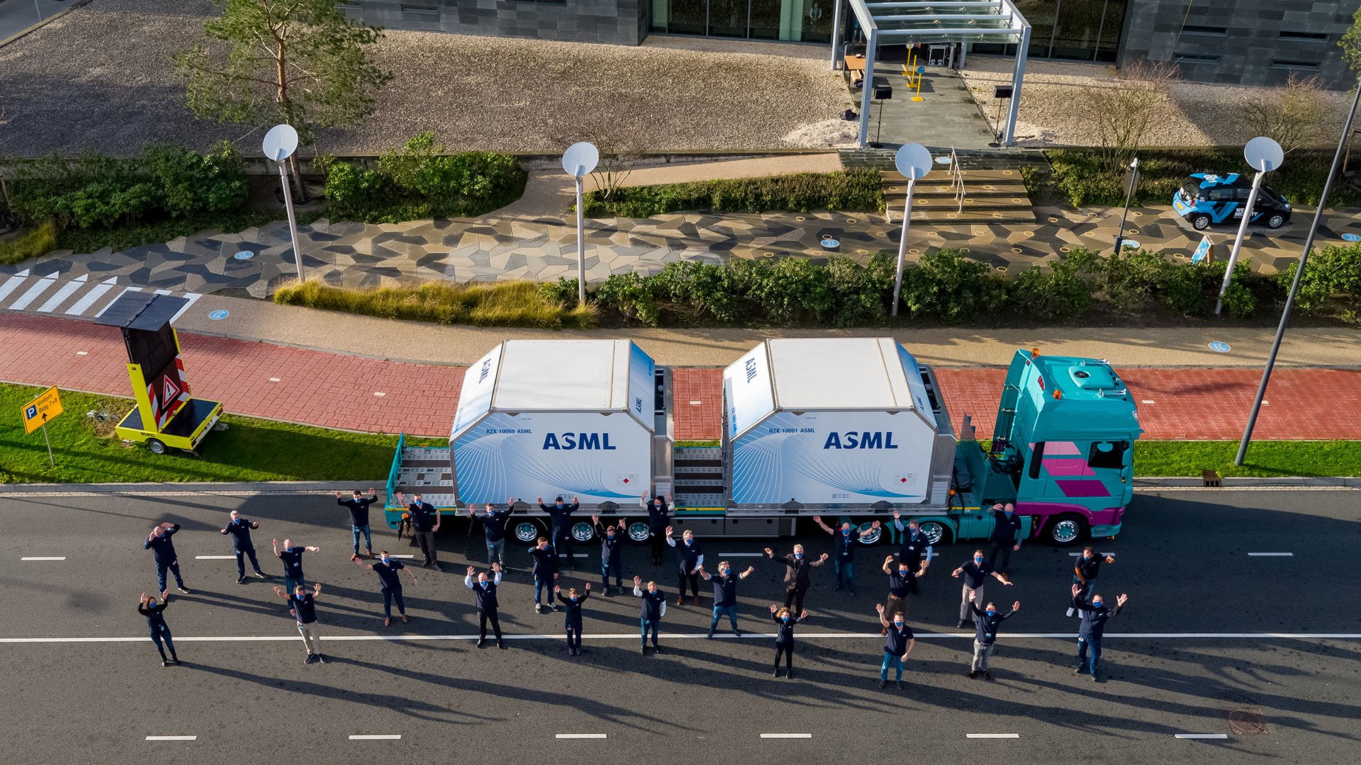 Employees stand with arms raised in front of truck containing the 100th ASML EUV machine Employees stand with arms raised in front of truck containing the 100th ASML EUV machine
