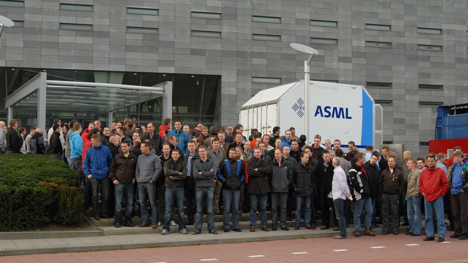 A group of employees stands in front of ASML headquarters in Veldhoven, the Netherlands to celebrate the first EUV machine shipment in 2010. A group of employees stands in front of ASML headquarters in Veldhoven, the Netherlands to celebrate the first EUV machine shipment in 2010.