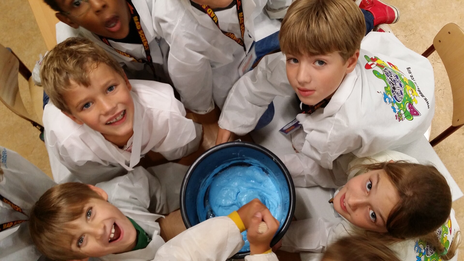 A picture of children making a blue mixture during a science experiment.