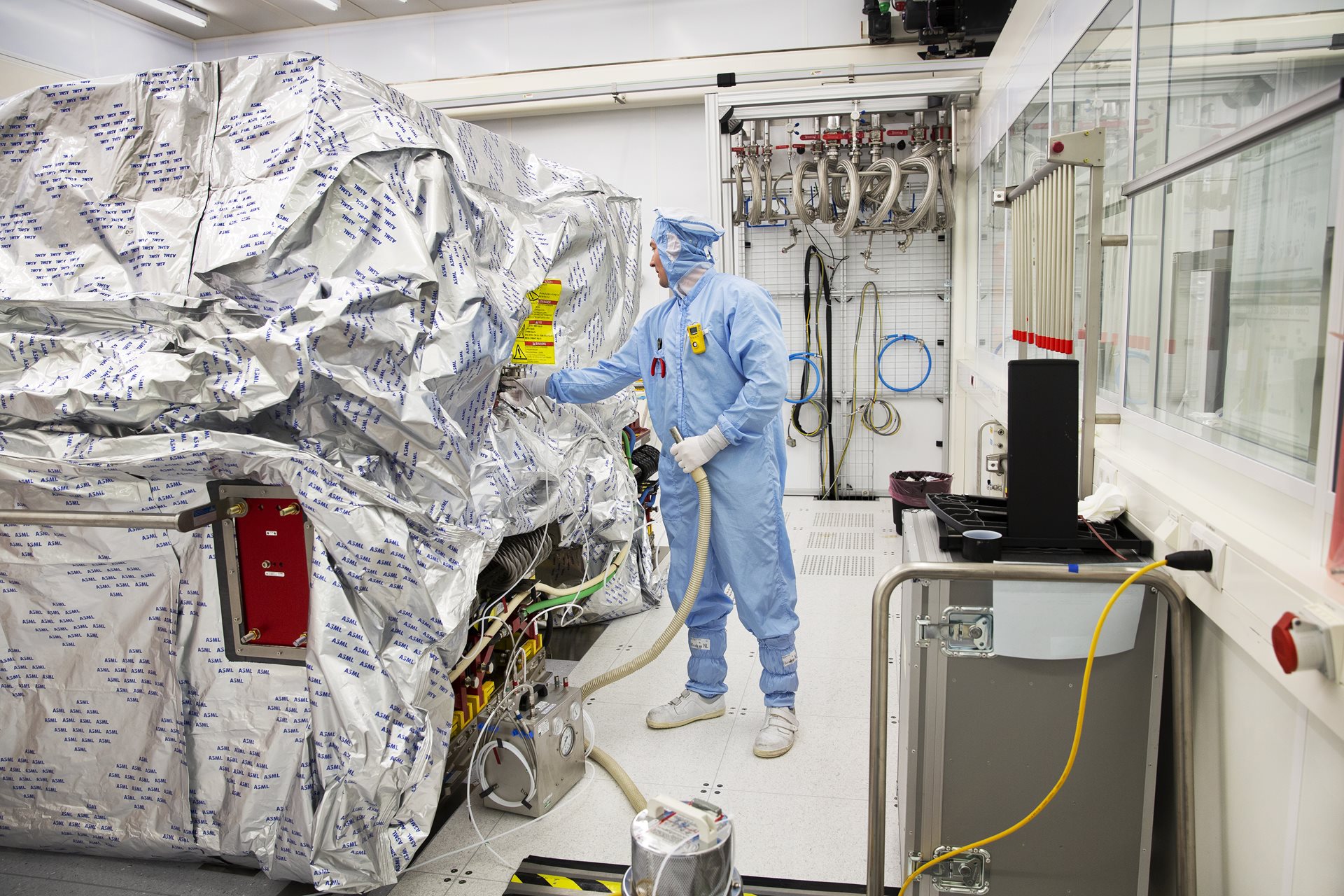 An ASML employee in a cleanroom suit works on a DUV lithography system. 