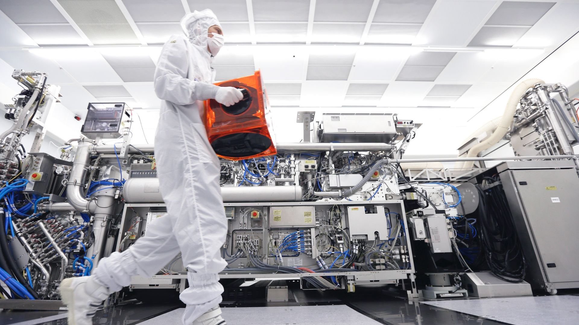 An ASML cleanroom technician carries a FOUP containing wafers. 