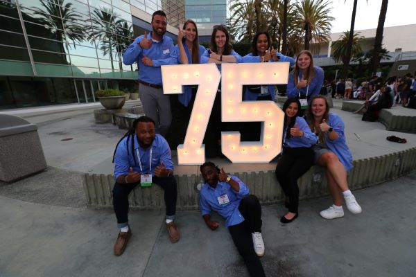 ADLM staff members sitting around a giant number 75 at the 2023 AACC Annual Scientific Meeting opening mixer.