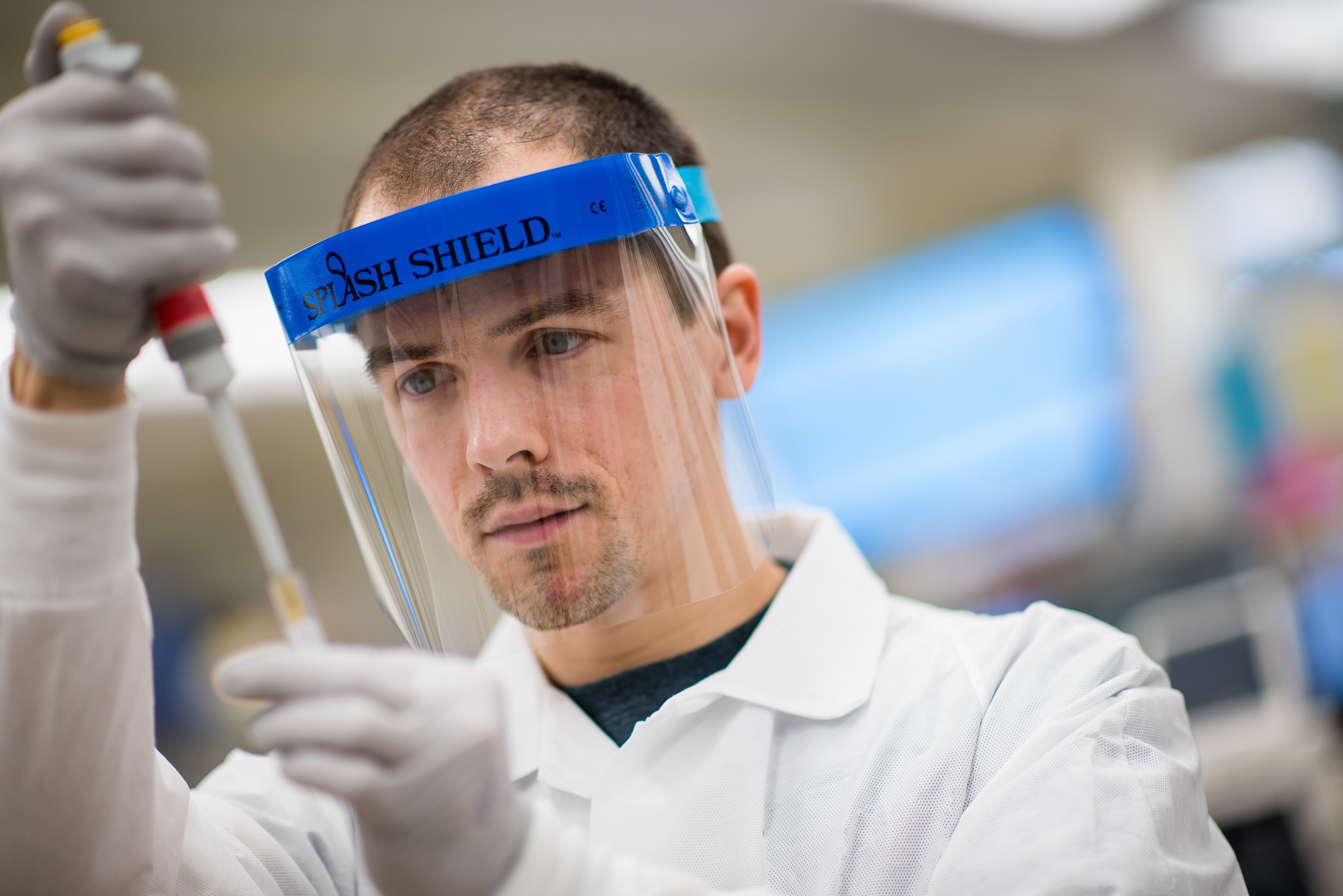 Male lab technician squeezing liquid into test tube