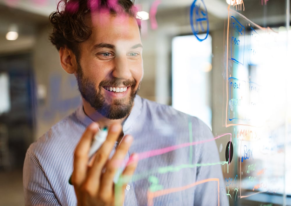 A man smiles while working with an interactive screen showing data analytics graphics.