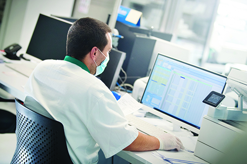 A male laboratorian sitting at a desk on a computer