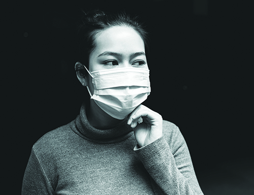 A black and white image of a woman in a mask looking off to the side