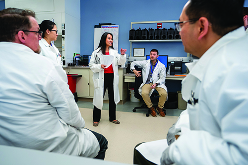 A female laboratorians speaking to other laboratorians around her