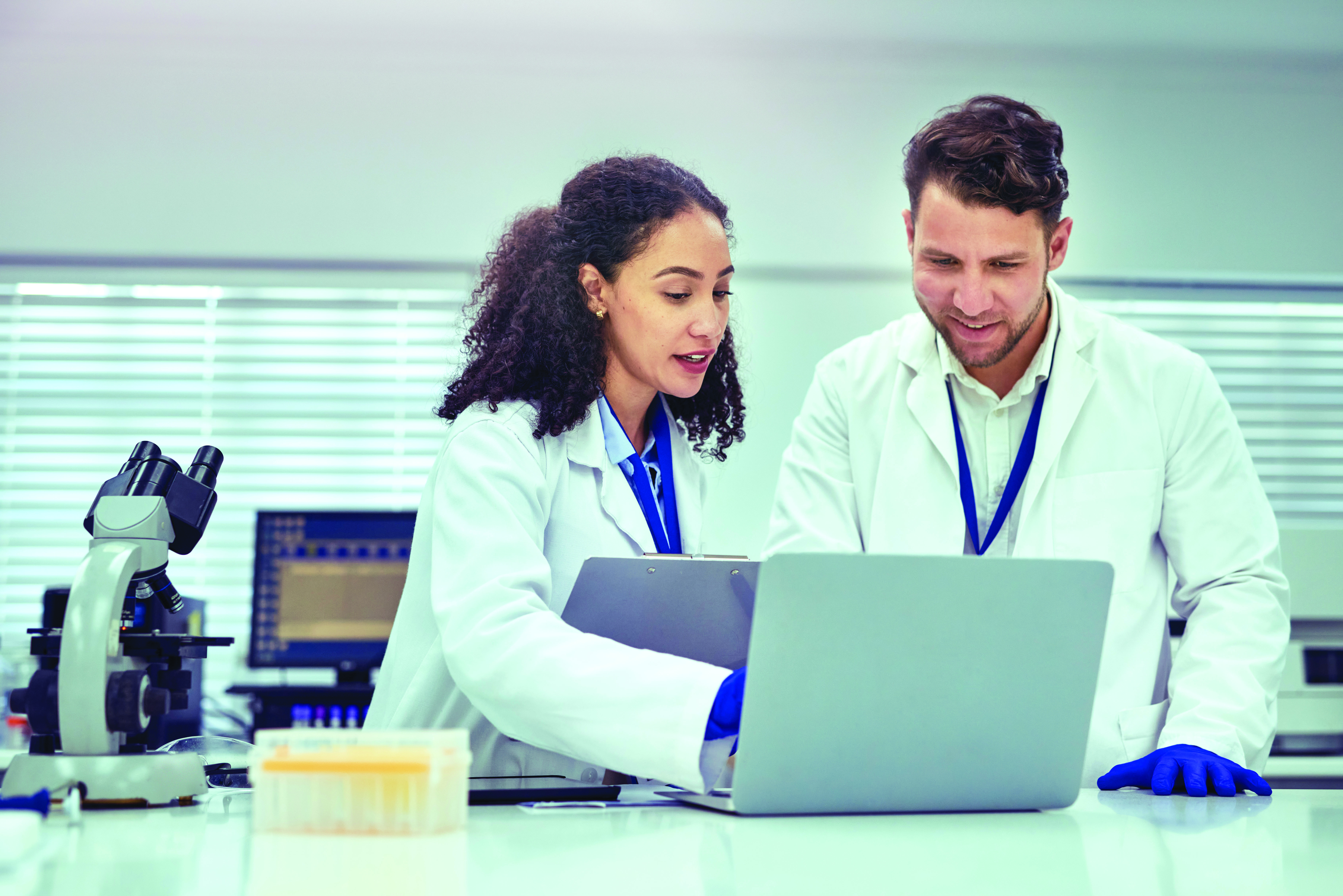 two lab workers at a laptop