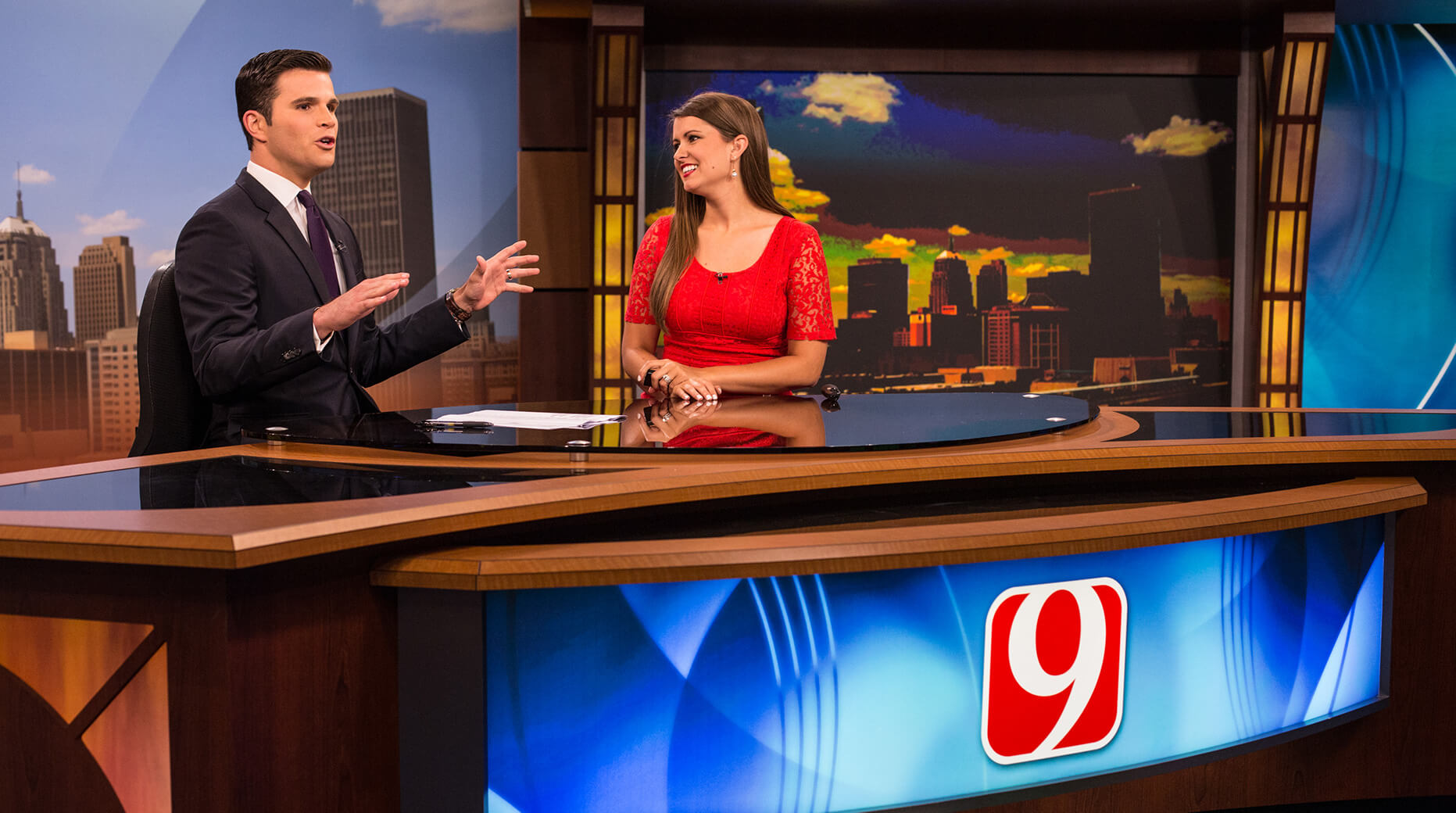 two anchors seated at news desk in studio