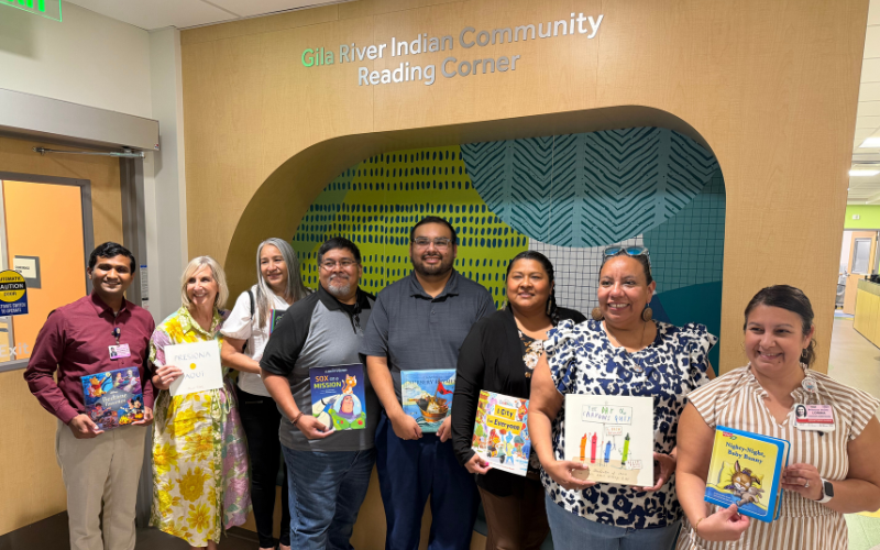 A group of eight people stand in front of a wall that reads 
