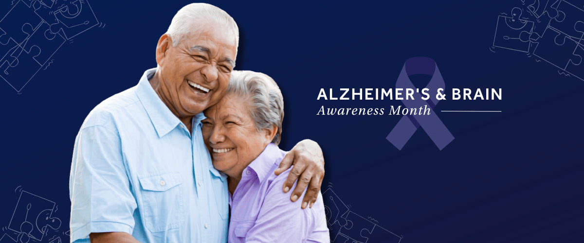 A smiling couple embracing, with the man wearing a light blue shirt and the woman wearing a lavender shirt.