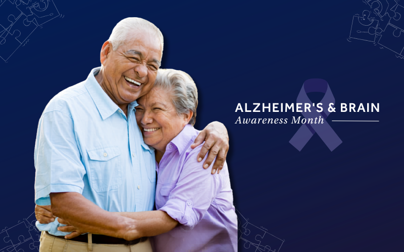 A smiling couple embracing, with the man wearing a light blue shirt and the woman wearing a lavender shirt.