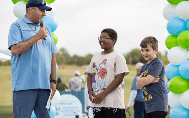 Dr. Rahul Chawla talking to pediatric patients Kaleb and Owen at golf tournament.