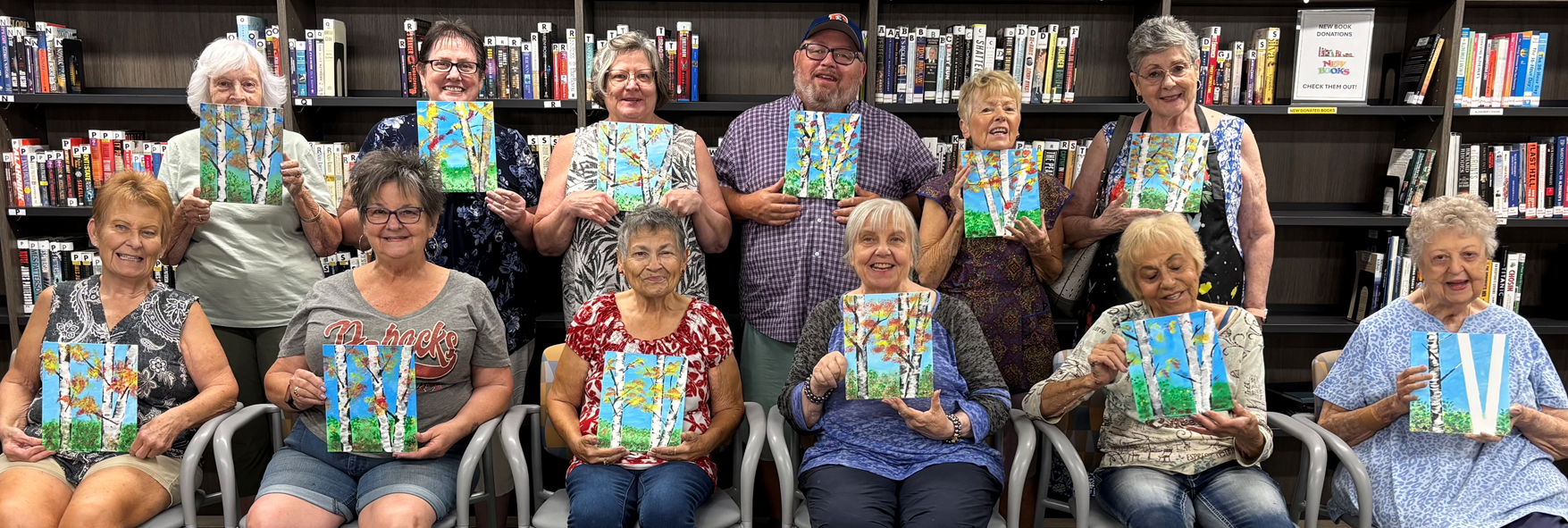 Group of seniors displaying art class paintings. 