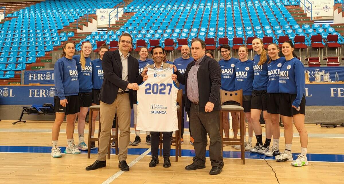 Jugadoras del BAXI Ferrol y representantes institucionales posan en una pista de baloncesto con una camiseta conmemorativa de 2027