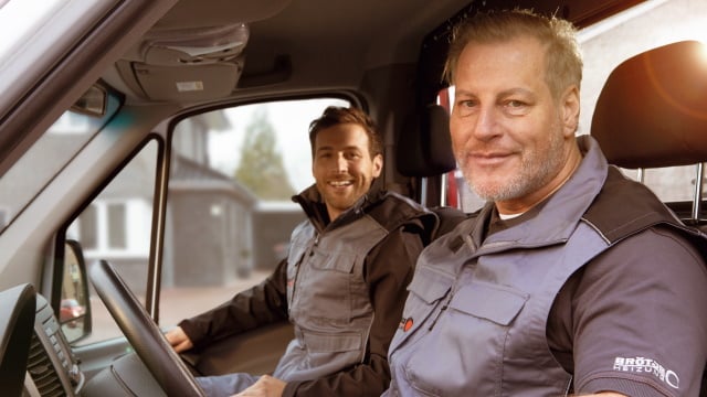 Zwei BRÖTJE Mitarbeiter im Auto blicken in die Kamera