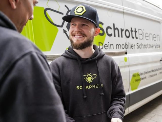 Mitarbeiter der Schrottbienen im Gespräch mit einem Kunden vor seinem Wagen