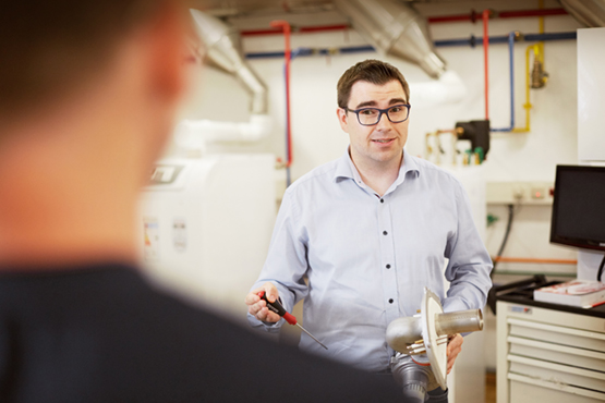 Ein Techniker spricht mit einem Kunden in der Nähe der Heizungsanlage