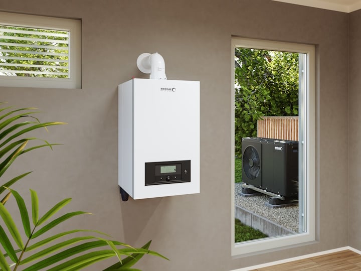 Der Gasbrennwertwandkessel WBS.2 hängt an der Wand eines Einfamilienhauses, vor der Tür steht eine Wärmepumpe