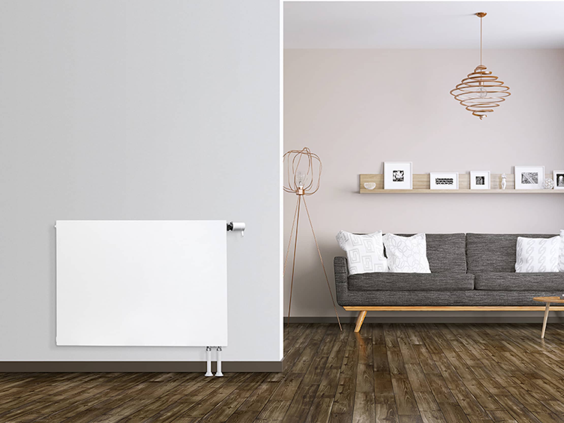 Ein EuroPlan-Flachheizkörper an einer hellgrauen Wand, rechts ein Wohnzimmer mit einer Couch.