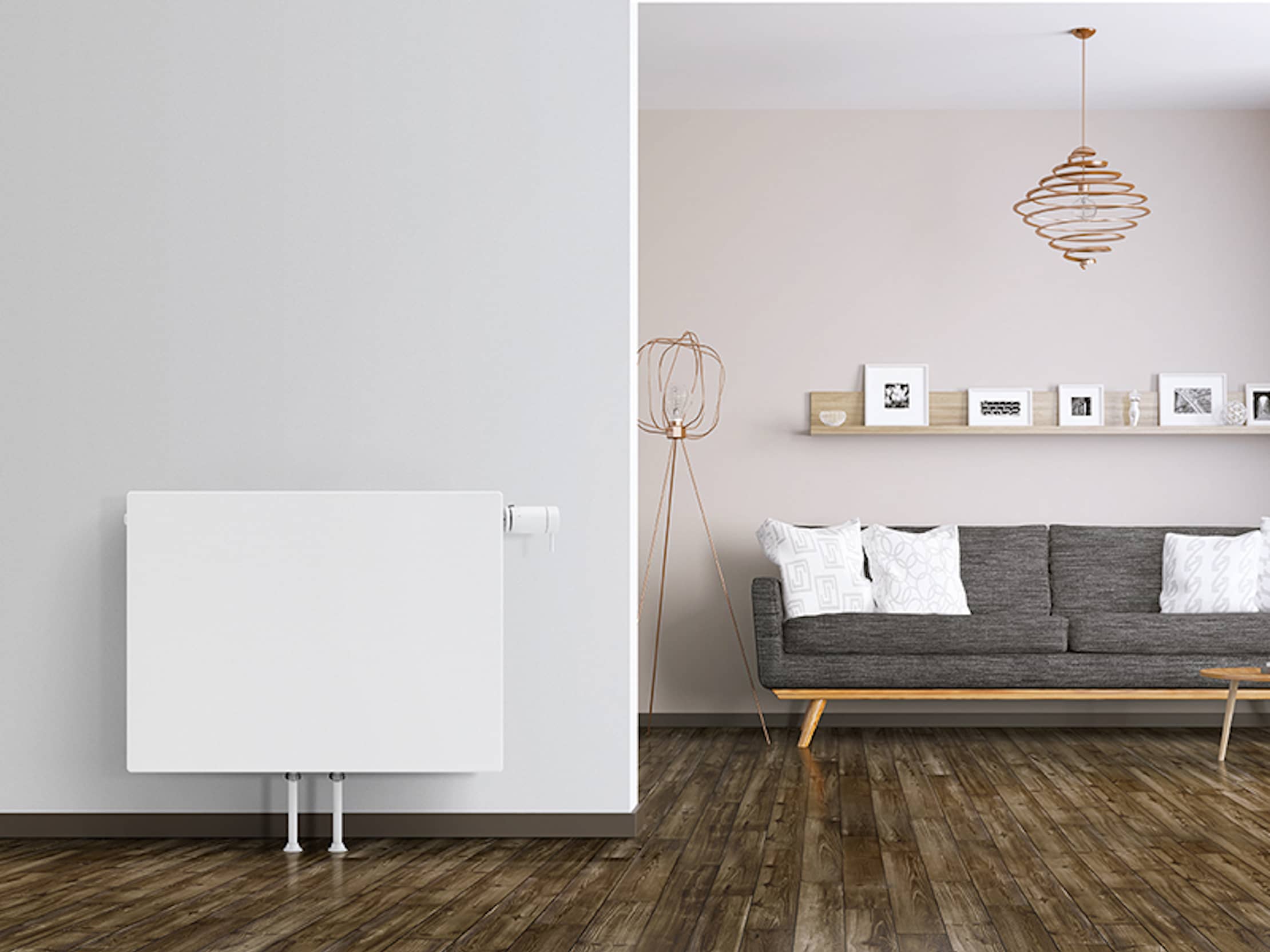 Ein MidiPlan-Flachheizkörper an einer hellgrauen Wand, rechts ein Wohnzimmer mit einer Couch.