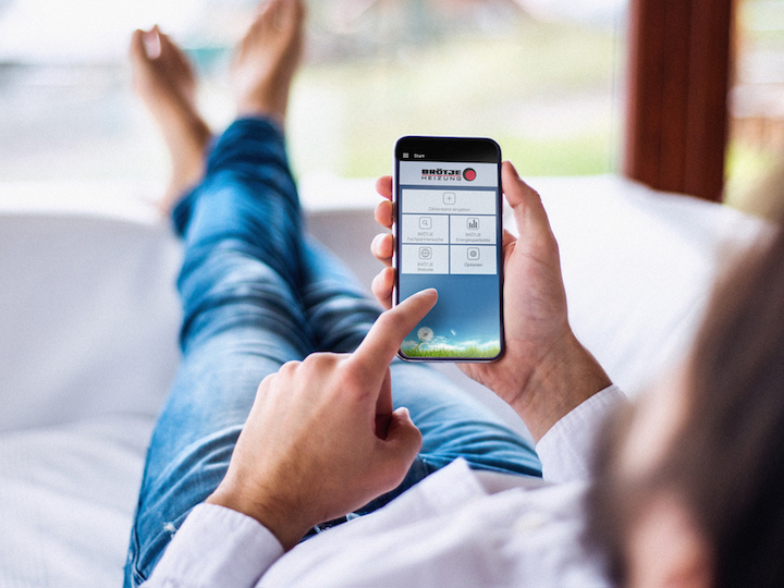 Mann liegt entspannt auf der Couch und bedient eine BRÖTJE App