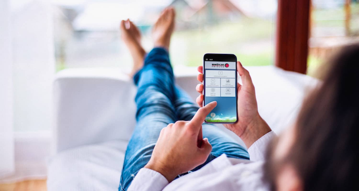 Mann liegt entspannt auf der Couch und bedient eine BRÖTJE App